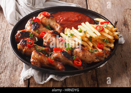 Servire Alette di pollo fritte con patatine e salsa su una piastra di close-up orizzontale. Foto Stock