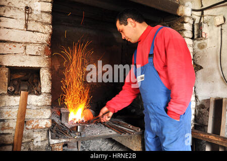 LUPENI, Romania - 19 Aprile 2012: Unidentified fabbro lavora su un oggetto nel caldo del carbone durante un workshop Foto Stock