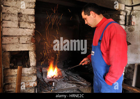 LUPENI, Romania - 19 Aprile 2012: Unidentified fabbro lavora su un oggetto nel caldo del carbone durante un workshop Foto Stock