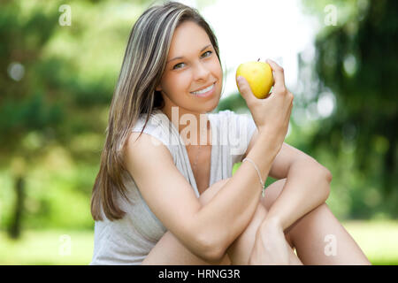 Ragazza avente un sano apple snack seduti al parco Foto Stock