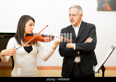 Insegnante di violino di aiutare uno studente presso il conservatorio Foto Stock