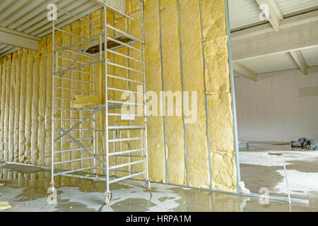 Impalcatura mobile viene utilizzato per completare la parete divisoria con isolamento termico, la lana minerale. Foto Stock