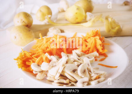 Ingredienti per la zuppa, carote e funghi sulla piastra, primo piano Foto Stock