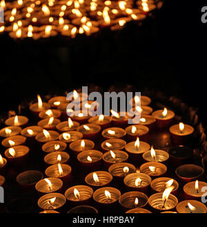 Molte candele accese con la calda fiamma durante la cerimonia religiosa Foto Stock