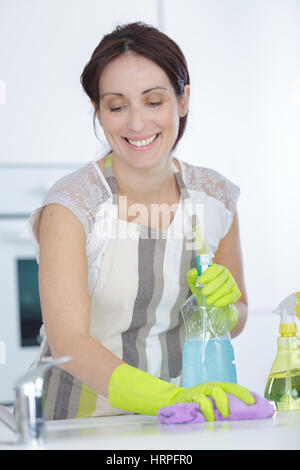 Sorridente giovane donna pulizia di mobili in cucina Foto Stock