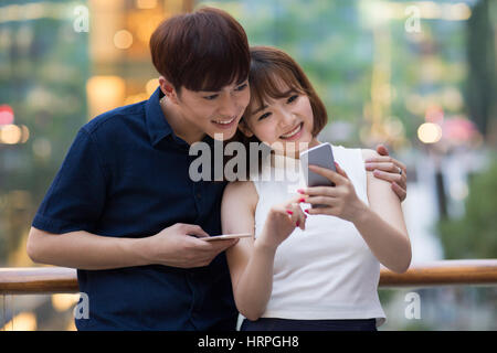 Felice coppia giovane con l'utilizzo di telefoni smart Foto Stock