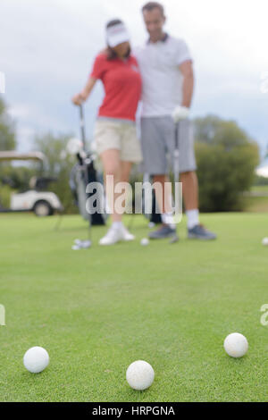 Palline da golf sul green con un paio di golf in background Foto Stock