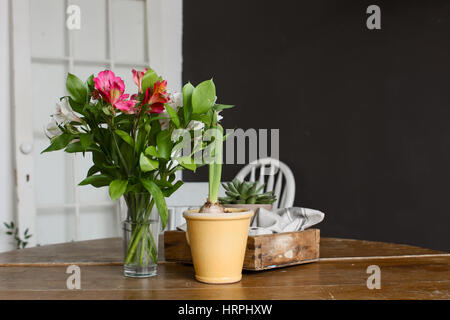 Vaso e un vaso con fiori in piedi sul legno tavolo rotondo. Foto Stock