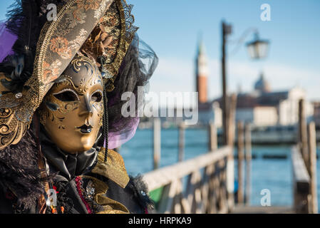 Golden Carnevale veneziano maschera. Splendida maschera partecipante dei festeggiamenti carnevaleschi in bacino San Marco. Sfondo sfocato. Foto Stock