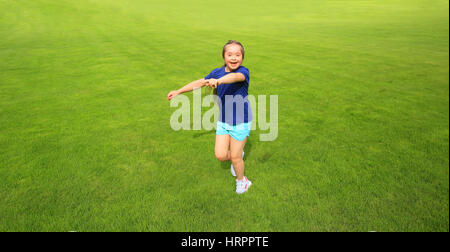 Bambina in esecuzione su erba verde sullo sfondo Foto Stock