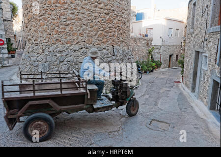 Un uomo aziona il suo triciclo attraverso gli stretti vicoli del borgo medievale di Mesta, Chios, Grecia Foto Stock