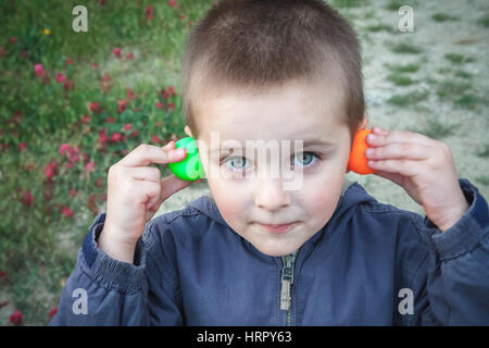 Kid giocando con colorato ping pong palla rendendo volti Foto Stock