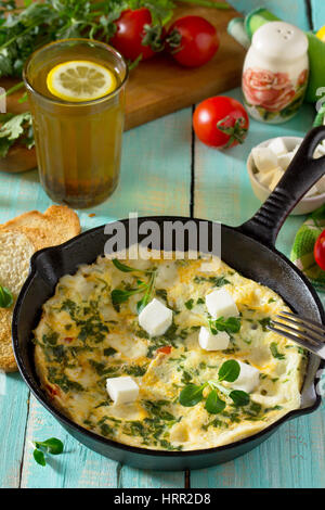 Frittata con peperoni, pomodori e formaggio feta in una ghisa padella su di un tavolo di legno. Il concetto di una sana nutrizione e dietetica. Il bulgaro cuis Foto Stock