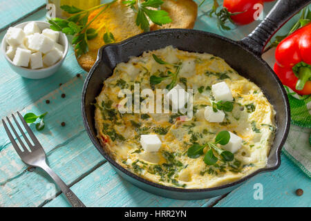 Frittata con peperoni, pomodori e formaggio feta in una ghisa padella su di un tavolo di legno. Il concetto di una sana nutrizione e dietetica. Il bulgaro cuis Foto Stock