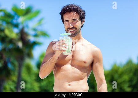 Bel giovane bevendo un cocktail mentre vi rilassate in piscina Foto Stock