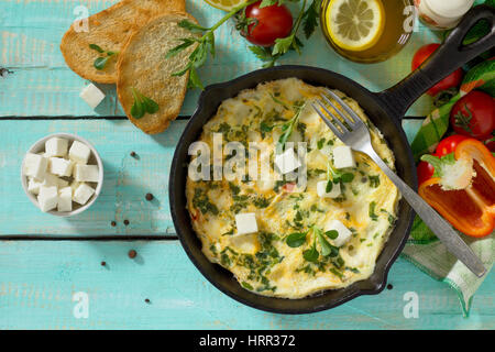 Frittata con peperoni, pomodori e formaggio feta in una ghisa padella su di un tavolo di legno. Il concetto di una sana nutrizione e dietetica. Il bulgaro cuis Foto Stock