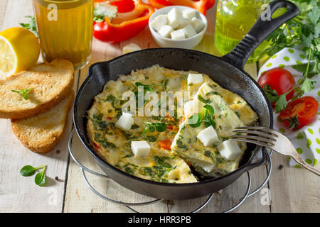Frittata con peperoni, pomodori e formaggio feta in una ghisa padella su di un tavolo di legno. Il concetto di una sana nutrizione e dietetica. Il bulgaro cuis Foto Stock