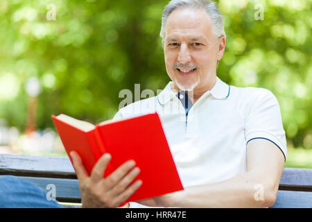 Uomo maturo la lettura di un libro per esterno Foto Stock