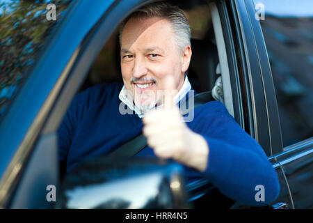 Felice uomo maturo alla guida della sua auto Foto Stock