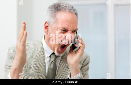 Imprenditore arrabbiato grida al telefono Foto Stock