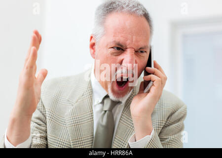 Imprenditore arrabbiato grida al telefono Foto Stock