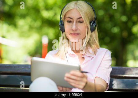 Ritratto di una donna matura ascoltando musica all'aperto Foto Stock