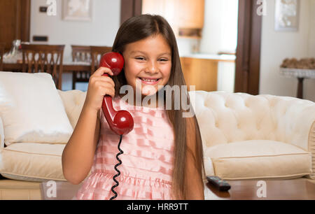 Sorridente bambina a parlare su un telefono vintage a casa Foto Stock