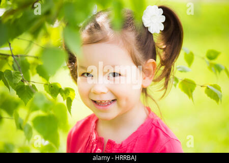 Closeup ritratto di carino divertente ragazza ridere di quattro anni a giocare allegramente fuori in primavera soleggiata città park. Orizzontale fotografia a colori. Foto Stock