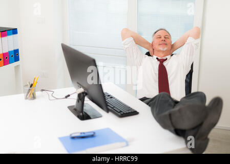 Uomo maturo rilassante nel suo ufficio Foto Stock