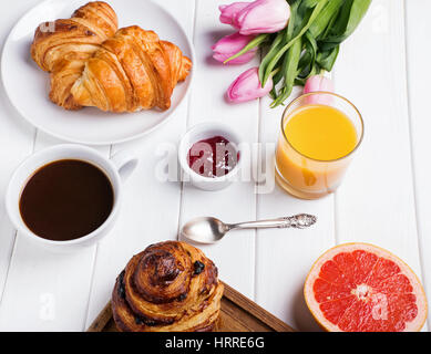 La prima colazione con la pasticceria, caffè e succo di arancia sul tavolo bianco Foto Stock
