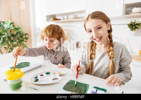 La creazione di una tavolozza. Appassionato di felice bellissima ragazza con un sacco di sfumature di verde nel suo disegno provando appena comprato colori mentre spendere tempo wi Foto Stock