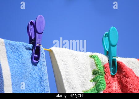 Colore luminoso asciugamani ancorata ad una linea di lavaggio contro un cielo blu chiaro Foto Stock