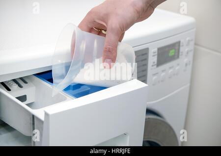 Il detersivo liquido di una bottiglia verde viene versato nella lavatrice.  Preparazione per lavaggio, dosatore per detersivo in polvere Foto stock -  Alamy