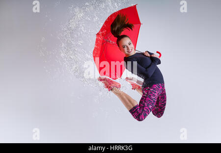 Donna in salto con un ombrello. Movimento congelato. Foto Stock