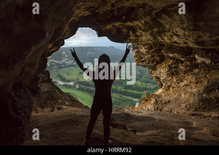 Giovane donna sta sollevando i bracci nella grotta di vittoria di finestra che si affaccia sul Rio Grande DE ARECIBO VALLEY PUERTO RICO Foto Stock