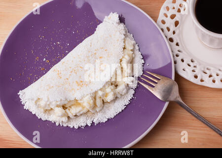 Casabe (ingaggiami, beiju, bob, biju) - flatbread di manioca (tapioca) con ricotta e miele e la tazza di caffè su sfondo di legno. Messa a fuoco selettiva Foto Stock