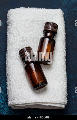 Due bottiglie di olio essenziale su un asciugamano bianco. vista dall'alto, il fuoco selettivo Foto Stock