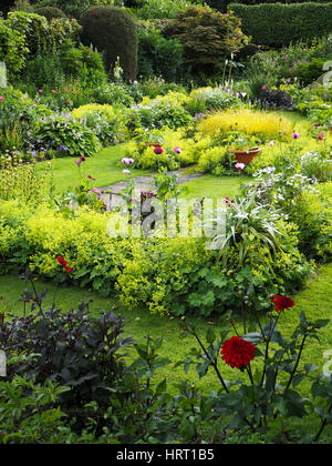 Visualizzazione verticale di Chenies Manor sunken garden, Buckinghamshire. Verde e rigogliosa la crescita con colorate dalie, hosta foglie e piante erbacee. Foto Stock