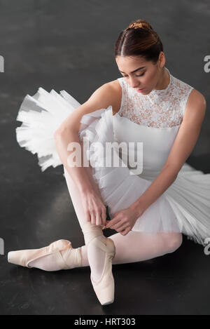 Bellissima ballerina in posa nella classe di balletto, barre e muro bianco su sfondo Foto Stock