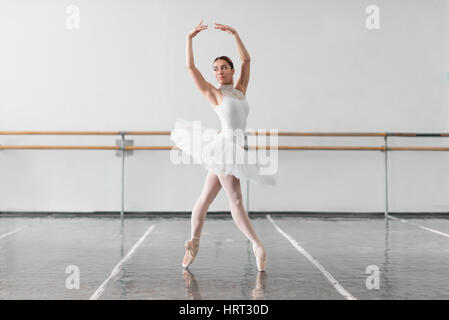 Bellissima ballerina prova nelle lezioni di ballo, barre e muro bianco su sfondo Foto Stock