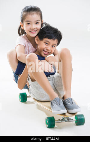 Carino piccolo ragazzo e ragazza che gioca con lo skateboard Foto Stock