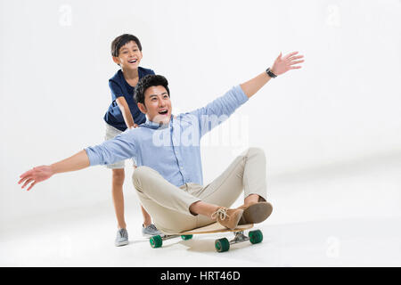 Padre e figlio giocare con lo skateboard Foto Stock