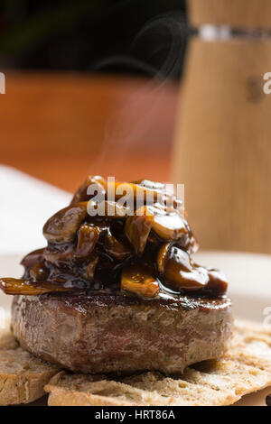 Bistecca di manzo ricoperta di filetto con salsa di funghi su tostati Pane baguette con burro di fusione e le erbe aromatiche Foto Stock