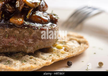 Bistecca di manzo ricoperta di filetto con salsa di funghi su tostati Pane baguette con burro di fusione e le erbe aromatiche Foto Stock