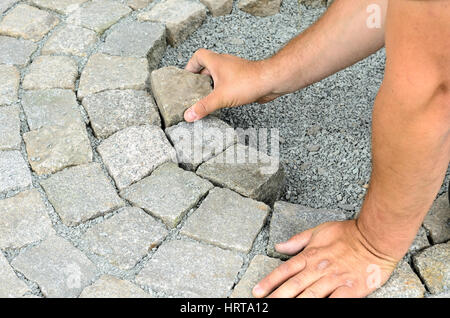 Operaio edile l'installazione di blocchi di pietra sul marciapiede Foto Stock