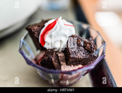 Piccolo brownie ciotola con panna montata e salsa di cherry topping Foto Stock