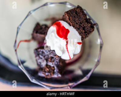 Piccolo brownie ciotola con panna montata e salsa di cherry topping Foto Stock