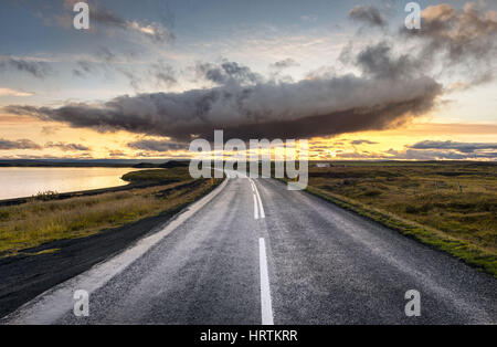 Myvatn, Islanda - unica cloud drammatico al di sopra di un vuoto che la strada che conduce al tramonto Foto Stock