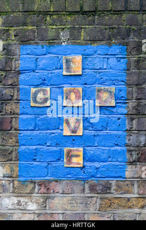 Muro di mattoni dipinto di blu con amore di Dio su di essa Foto Stock