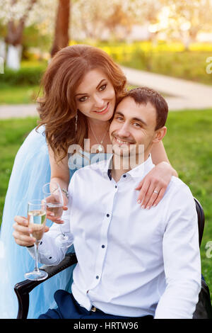 Lo sposo e la sposa insieme, coppie in viaggio di nozze. Coppia giovane abbracciando, bevendo champagne in primavera in fiore giardino. Amore e tema romantico Foto Stock